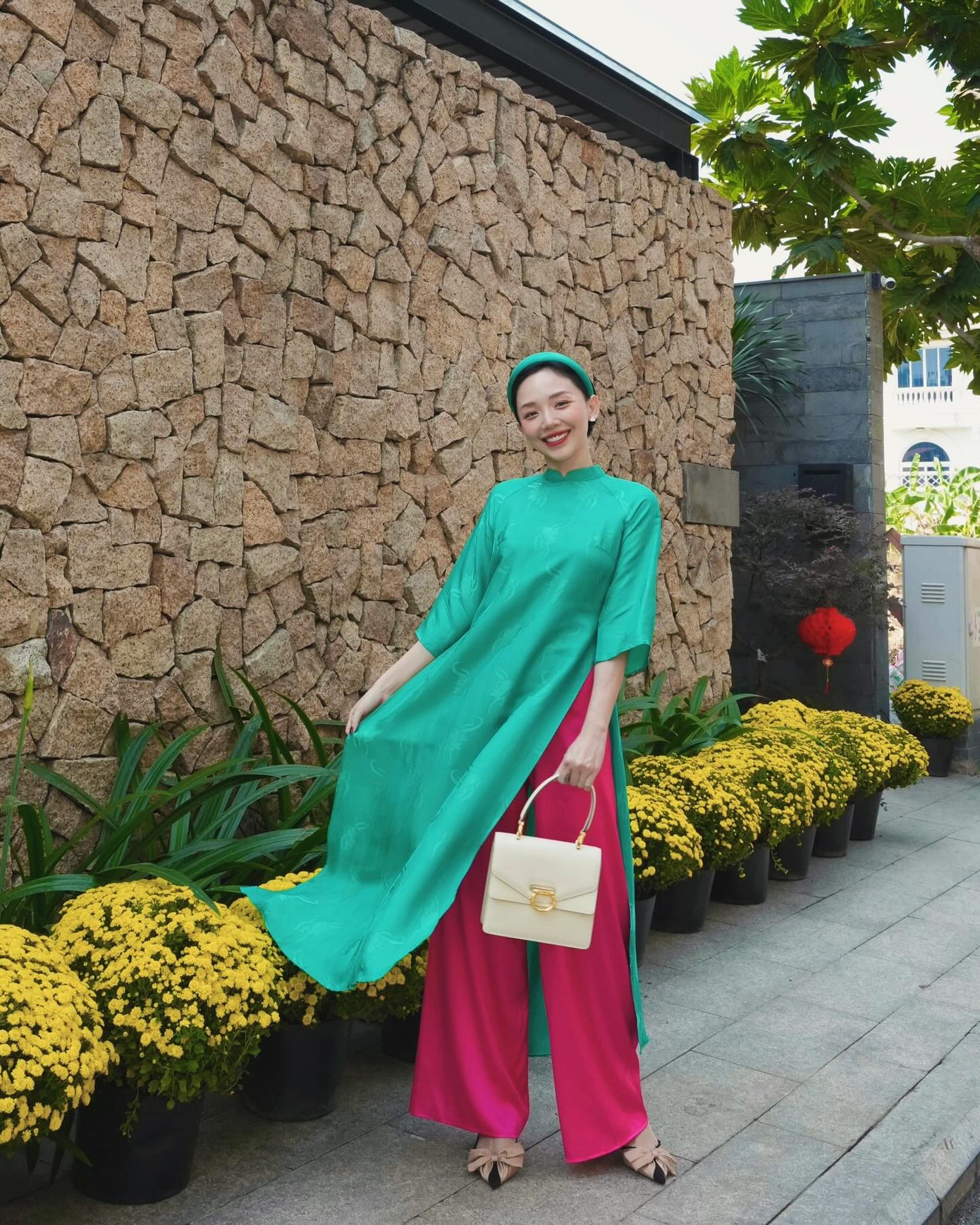 Tóc Tiên trẻ trung với tà áo dài dáng suông màu xanh, kết hợp với quần màu hồng nổi bật.
