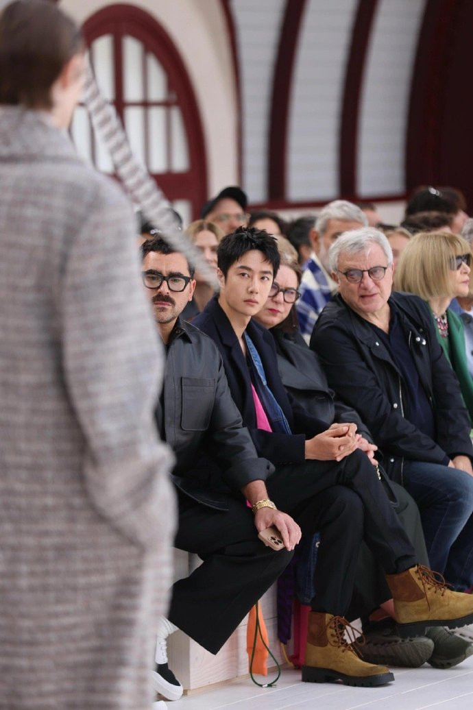 Vương Nhất Bác ngồi hàng ghế đầu, bên cạnh bà Pascale Lepoivre (CEO của thương hiệu LOEWE) và Dan Levy - nam diễn viên người Canada. Vương Nhất Bác ngồi hàng ghế đầu, bên cạnh bà Pascale Lepoivre (CEO của thương hiệu LOEWE) và Dan Levy - nam diễn viên người Canada.
