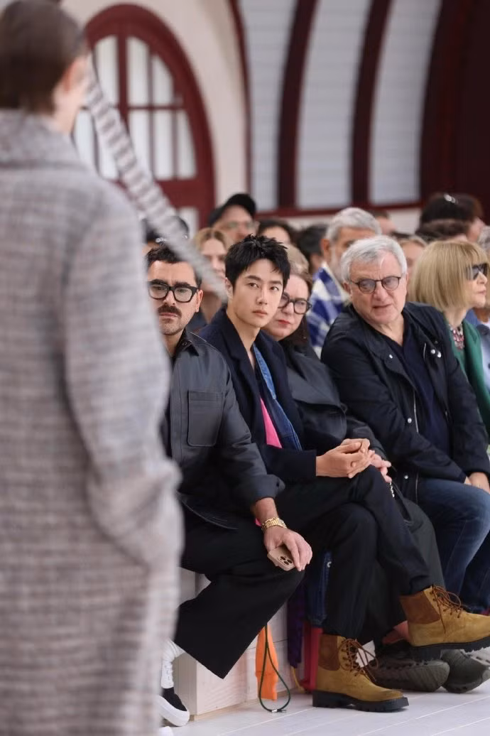 Vương Nhất Bác ngồi hàng ghế đầu, bên cạnh bà Pascale Lepoivre (CEO của thương hiệu LOEWE) và Dan Levy - nam diễn viên người Canada.