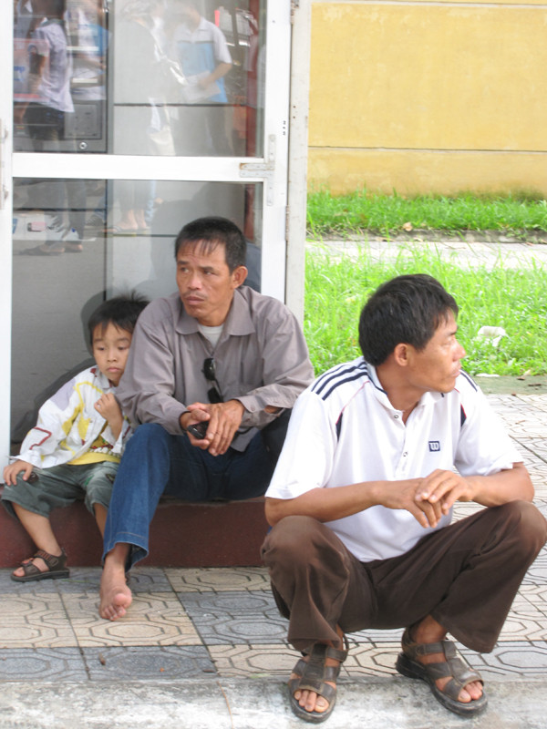 Hai bố con ngồi chờ anh cả làm thủ tục dự thi tại ĐH Bách khoa Hà Nội