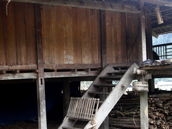 Cầu thang lên nhà làm bằng gỗ. (Trong ảnh: cầu thang có thêm cánh cửa đơn giản)