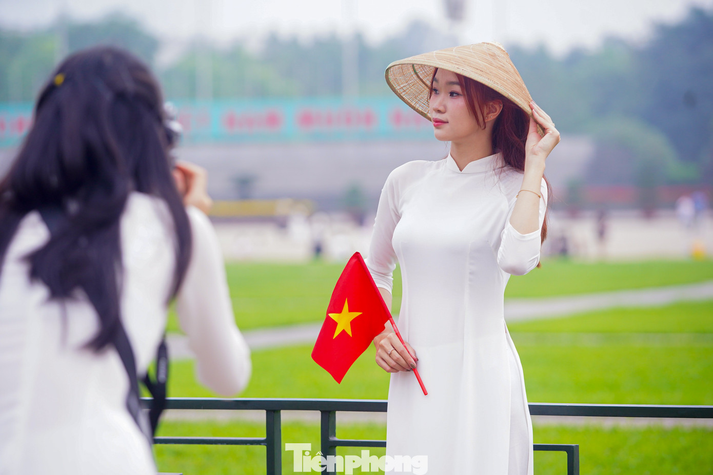 Thiếu nữ xúng xính trong bộ áo dài cùng cờ đỏ sao vàng chụp ảnh trước Quảng trường Ba Đình.