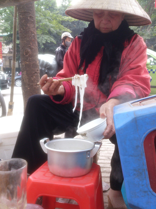 Hơn 10 năm nay, cụ bà này vẫn ngồi bán trà đá, kẹo lạc ở góc phố Trần Hưng Đạo – Phan Bội Châu (quận Hoàn Kiếm, Hà Nội). Cụ cho biết, quê gốc ở Nam Định, không có gia đình, con cái. Bữa trưa của cụ đơn giản chỉ có bát phở tự nấu bằng bếp than tổ ong nhờ của nhà dân cạnh đấy. 
