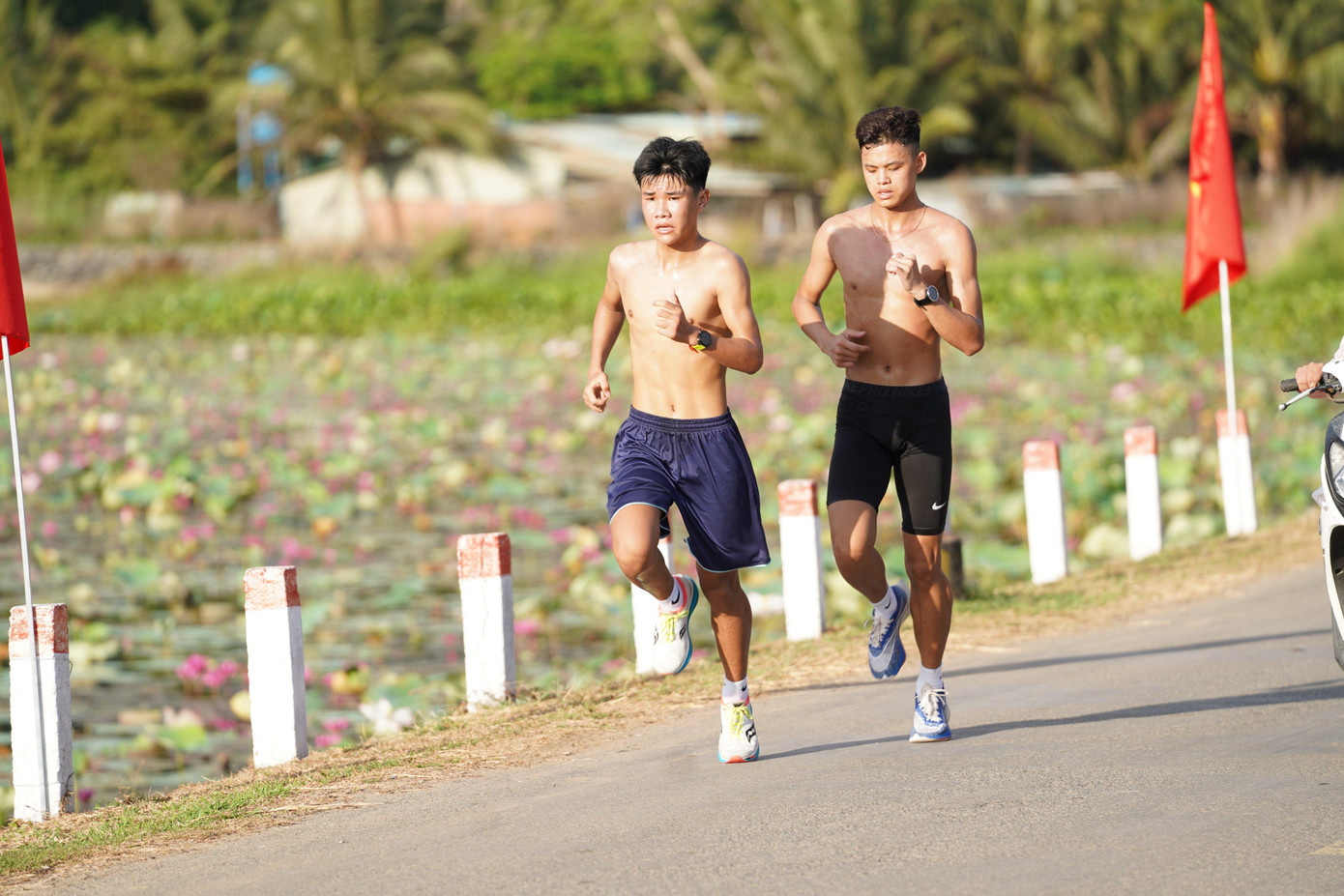 Hai VĐV của đoàn Bắc Giang chạy qua hồ An Hải đang nở rộ hoa súng.
