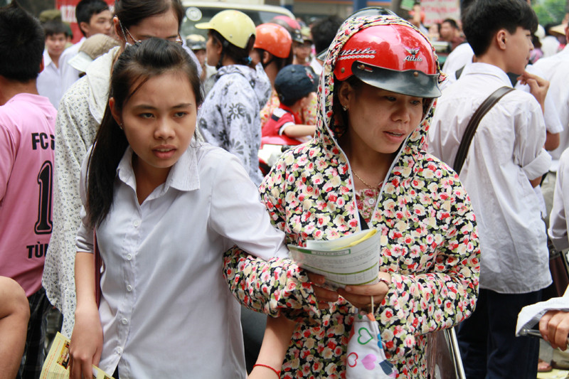Phải rất khó khăn, bậc phụ huynh này mới kéo được con gái mình ra khỏi vòng vây của những người phát tờ rơi. Trên tay hai mẹ con đều có một tập tờ rơi. Ảnh: Trường Phong