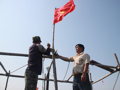 Thuyền trưởng Hay cùng các ngư dân cột chặt lá cờ Tổ quốc trước giờ xuất phát trực chỉ Hoàng Sa. Ảnh: nguyễn huy