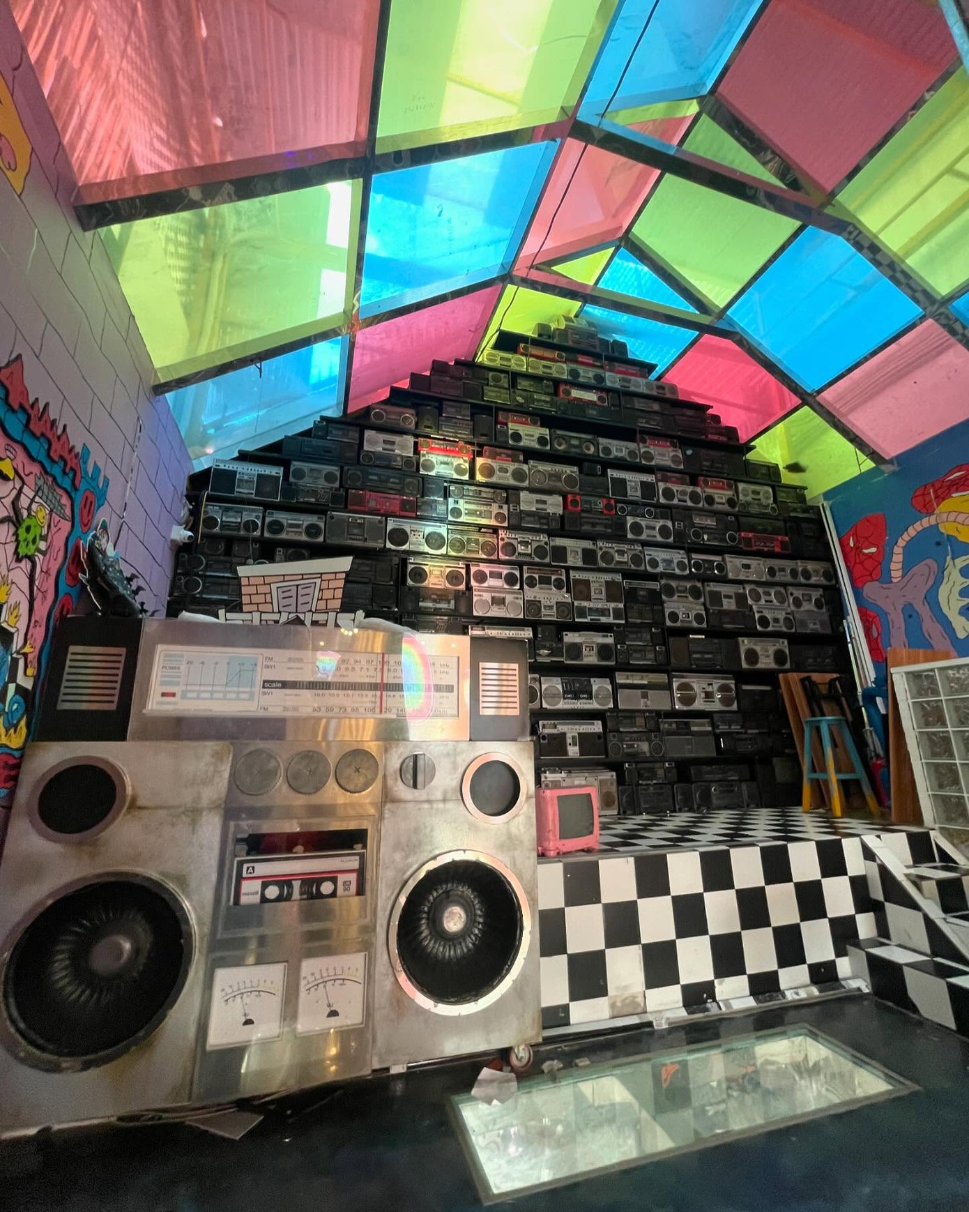 Tầng 2 với thiết kế mái vòm cùng những tấm kính nhiều màu sắc đem lại hiệu ứng phản quang thú vị. Đặc biệt, khu vực này có bức tường boombox được xếp chồng lên nhau mang lại cảm giác hoài cổ của thập niên 90. - Ảnh: Nirvana Space. Tầng 2 với thiết kế mái vòm cùng những tấm kính nhiều màu sắc đem lại hiệu ứng phản quang thú vị. Đặc biệt, khu vực này có bức tường boombox được xếp chồng lên nhau mang lại cảm giác hoài cổ của thập niên 90. - Ảnh: Nirvana Space.