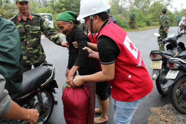 Bộ đội cùng nhân viên Chữ thập đỏ giúp một cụ già 87 tuổi đến nơi trú ẩn an toàn