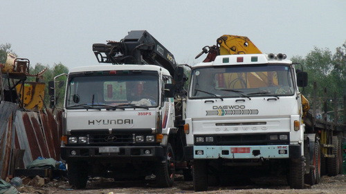 Bãi xe của một “đại gia” ở Bình Chánh, TP.HCM với bốn chiếc đầu kéo mang biển số đỏ. Theo ông này, xe của ông là xe dân sự, sau đó gắn biển số đỏ để kinh doanh. Ảnh: H.K. (Tuổi Trẻ)