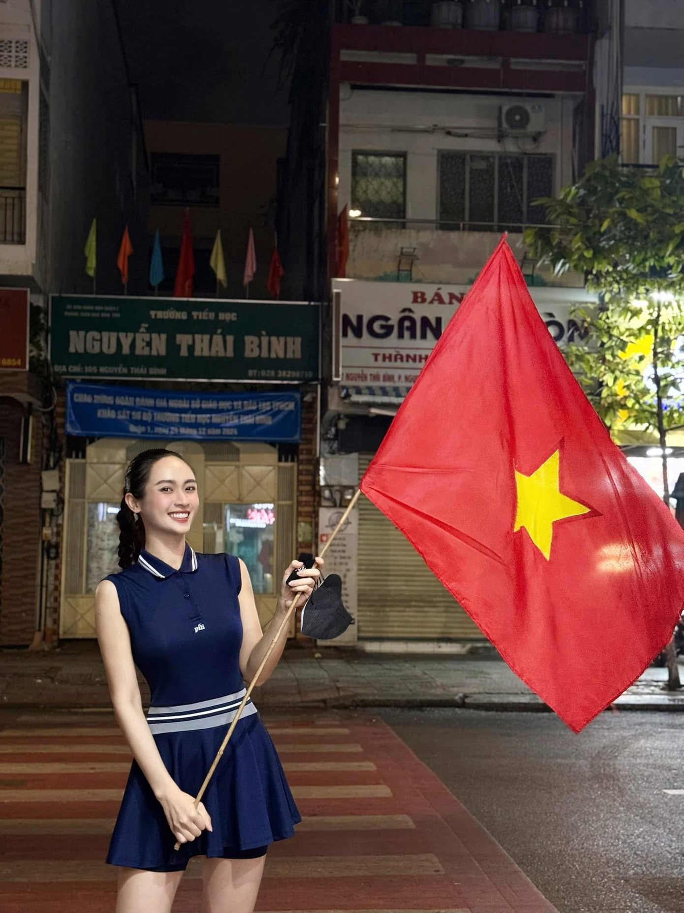 Á hậu Miss Universe Vietnam 2024 Vũ Thúy Quỳnh cầm cờ đỏ sao vàng, cổ vũ dòng người &quot;đi bão&quot; sau chiến thắng của đội tuyển Việt Nam.