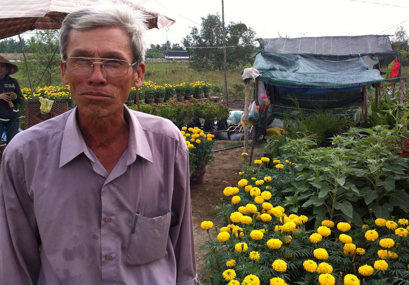 Ông Năm Bình bên cái chòi che lưới tạm bợ, mong muốn có chợ hoa tập trung với các dịch vụ tối thiểu 