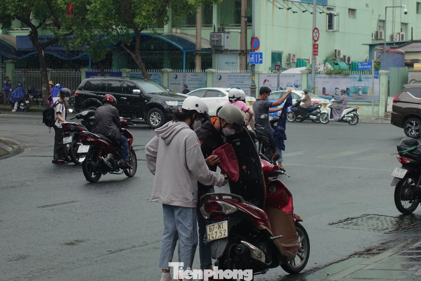 Cơn mưa bất chợt khiến nhiều người đi đường phải dừng phương tiện để mặc áo mưa.