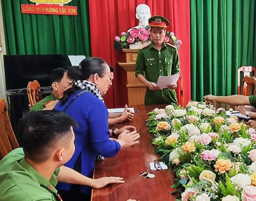 Công an tống đạt các quyết định khởi tố bà Lê Thị Kim L. (áo xanh dương).