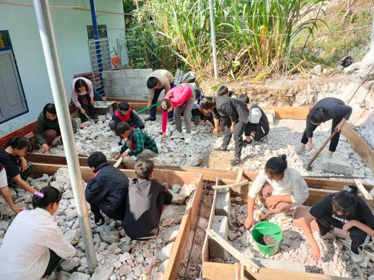 Phụ huynh, thầy và trò nhà trường tham gia làm nền cho khu nhà tắm