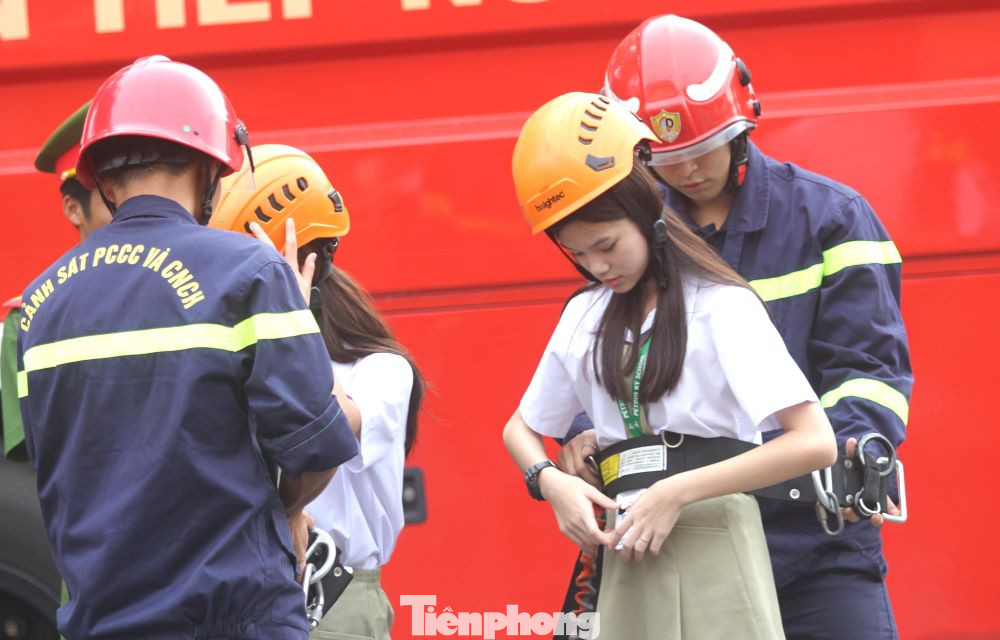 Các em học sinh được các chiến sĩ hỗ trợ trước khi lên xe thang chữa cháy.
