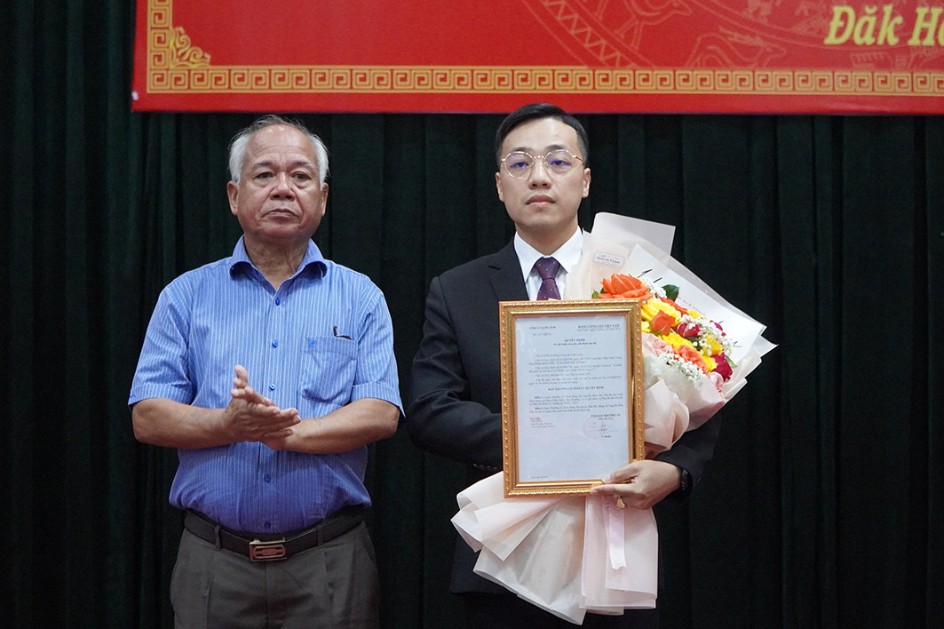 Phó Bí thư Thường trực Tỉnh ủy Kon Tum (trái) trao quyết định và tặng hoa chúc mừng tân Phó Bí thư Huyện ủy Đăk Hà.