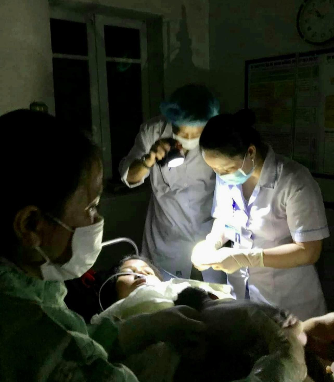 Trong hoàn cảnh mất điện, kíp trực phải dùng đèn dọi thực hiện ca đỡ đẻ lúc nửa đêm.