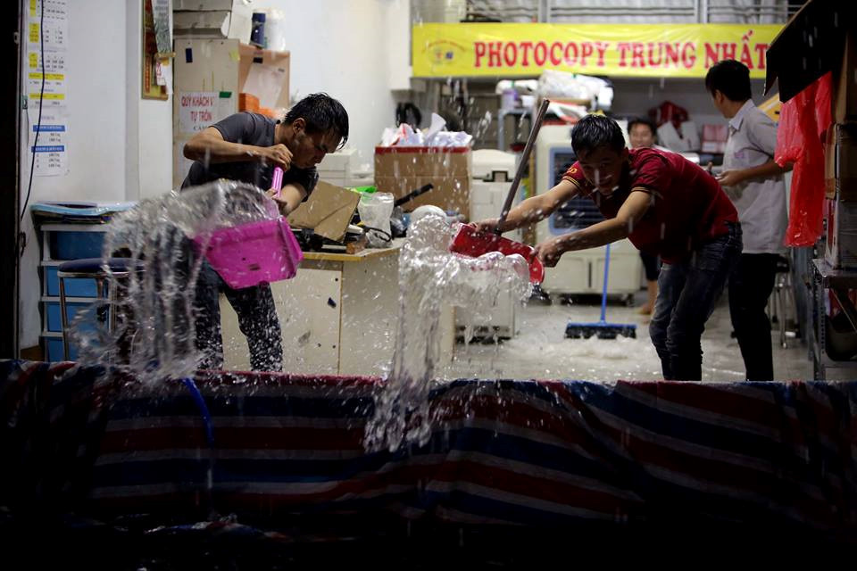 Người dân trên đường Nguyễn Hữu Cảnh (Q.Bình Thạnh, TP.HCM) tìm mọi cách ngăn nước tràn vào nhà, tối 25.11. ẢNH: NGỌC DƯƠNG