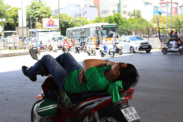 Một tài xế xe ôm ngả lưng dưới gầm cầu vượt đường Láng - Bưởi.