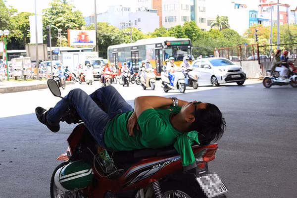 Một tài xế xe ôm ngả lưng dưới gầm cầu vượt đường Láng - Bưởi.