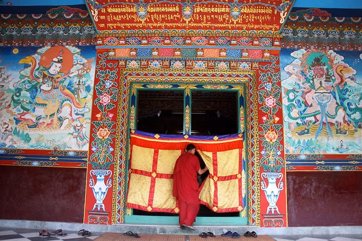 Một tu sĩ bước vào phòng cầu nguyện của tu viện Tharlam ở Boudhanath, Nepal.