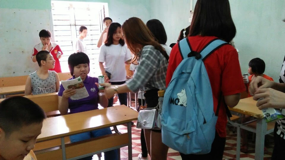 Các bạn sinh viên đang phát sữa cho các em nhỏ