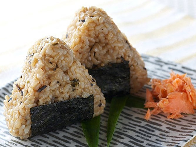 Onigiri là món cơm nắm hình tam giác vô cùng tiện lợi. Ngoài cơm trắng, còn có thể được trộn với cá hồi muối hoặc mơ muối.