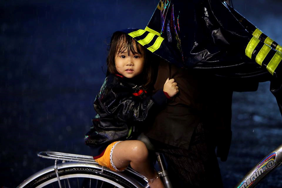 Cô bé nhỏ co ro sau chiếc xe đạp giữa trời mưa tầm tã vào tối 25.11 trên đường Quốc Hương (Q.2). ẢNH: NGỌC DƯƠNG.