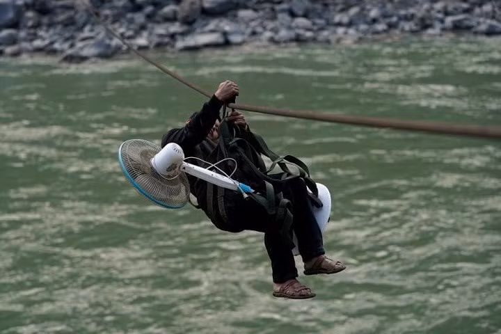 Một dân làng mang theo cả quạt cây khi đu qua sông.