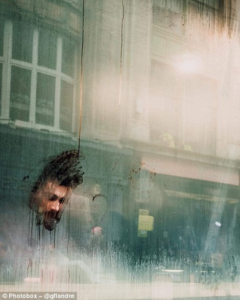 Một người đàn ông đang ngồi đọc sách phía sau cửa kính mờ hơi sương ở London