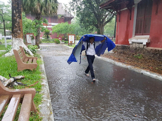 Một thí sinh tự mình đi vào phòng thi sau khi có chiếc áo mưa.