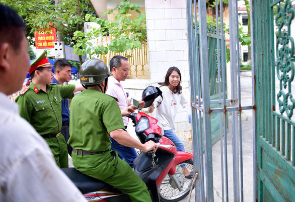 Thí sinh tức tốc vào phòng thi sau khi được hai cán bộ đưa đến điểm thi. (Ảnh: Tuổi Trẻ Online)