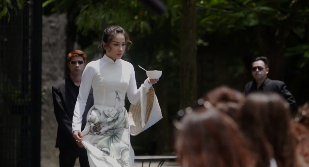 Khả Như có tạo hình nhu mì với “combo” áo dài và chén chè trên tay lượn lờ ở khu vực hồ bơi trong trailer.