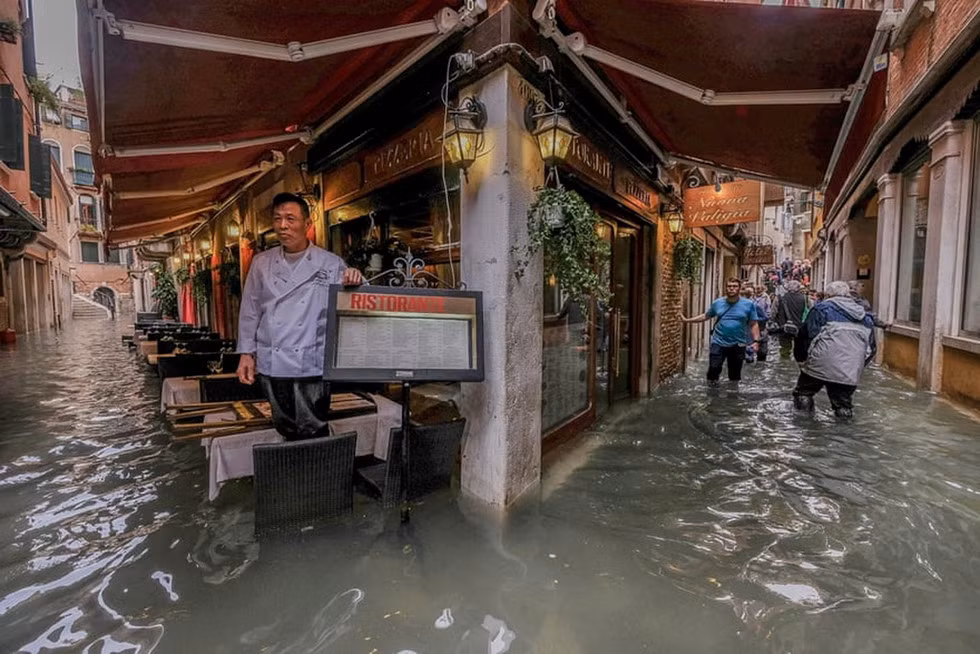 Một chủ nhà hàng ngao ngán nhìn nước lũ. Ảnh: AFP.