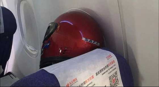 Chiếc mũ bảo hiểm cỡ lớn che kín mặt tuy khá nặng nhưng lại khá đảm bảo, có lẽ sẽ bảo vệ được hành khách này khỏi dịch bệnh.