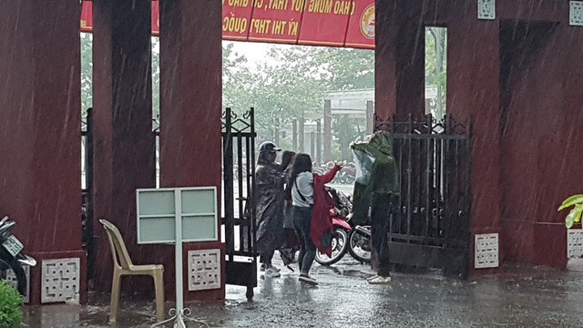 Những chiếc áo mưa đưa cho thí sinh để các em trùm vào người chạy vào phòng thi.