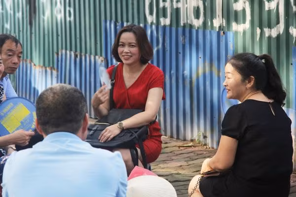 Bên ngoài điểm thi, phụ huynh ngồi trò chuyện đợi con em mình.