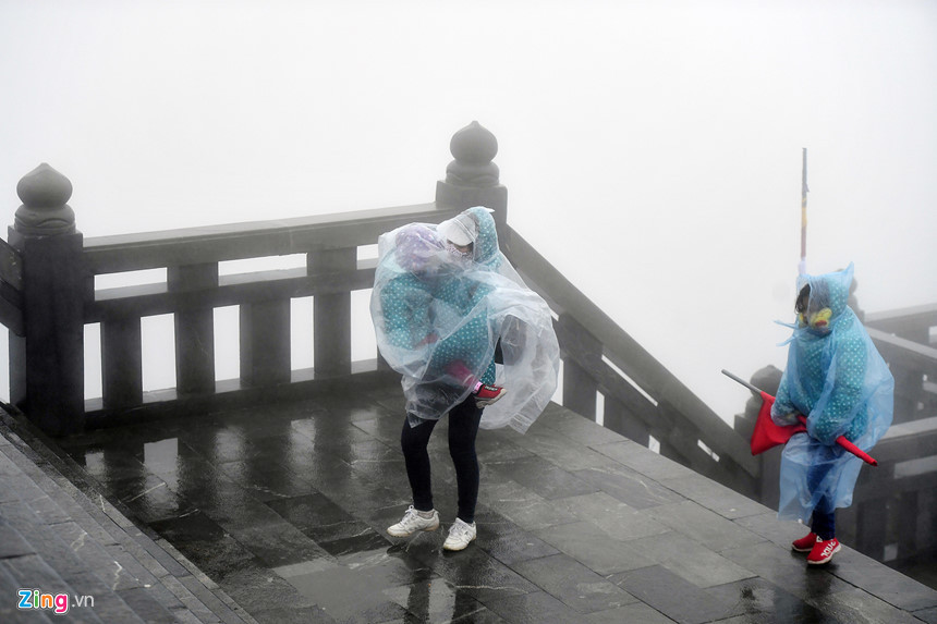 Trong khi đó, đỉnh Fansipan sáng và trưa 1/1 khá lạnh, có mưa nhỏ. Nhiều phụ huynh che chắn cẩn thận cho trẻ em cố gắng leo bậc thang lên nóc nhà Đông Dương.