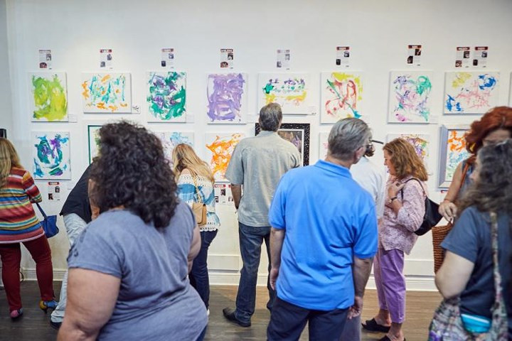 Nhiều khách tham quan đang chăm chú theo dõi các tác phẩm hội họa của những chú tinh tinh và đười ươi tại Khu bảo tồn Center For Great Apes. Những tác phẩm này đang được trưng bày tại Phòng triển lãm Frames USA &amp; Art Gallery ở Miami, Floria.