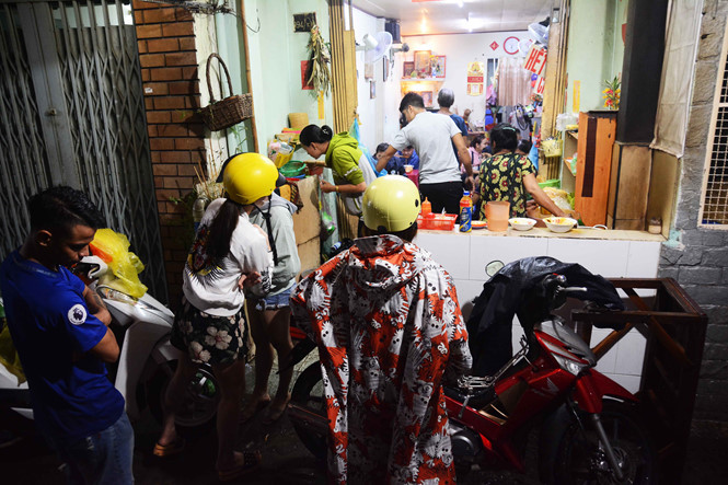 Nhiều người dù mưa vẫn kiên nhẫn đợi để mua được phần ăn mang về. ẢNH:HOÀI NHÂN.