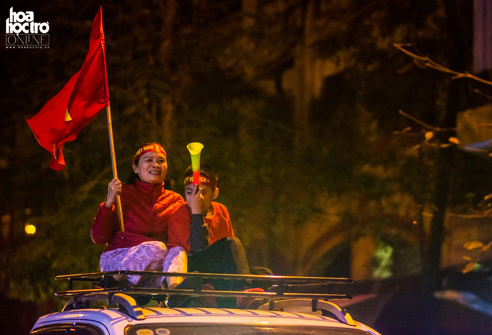 Hình ảnh 2 mẹ con ngồi trên nóc ôtô cầm theo cờ và kèn trên đường Hai Bà Trưng, Hà Nội.