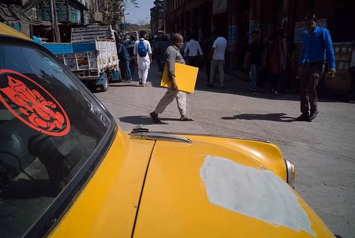 Liệu có mối liên hệ gì giữa tấm bảng màu vàng mà một người qua đường đang cầm và khoảng trống trên chiếc xe ô tô này hay không?