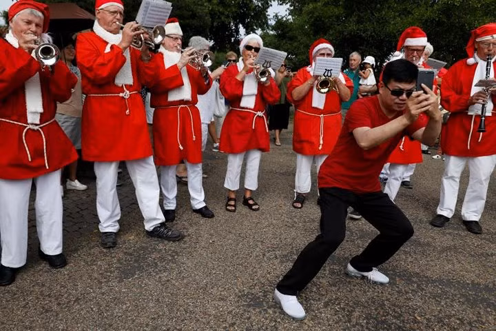 Một người đàn ông hào hứng tạo dáng chụp ảnh trước dàn nhạc của những ông già Noel./.