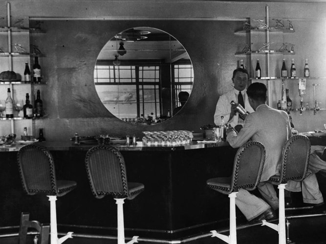 Từ rất lâu, các sân bay đã cung cấp dịch vụ ăn uống cho hành khách bởi những người đi máy bay thường phải đến rất sớm để làm thủ tục. Ảnh chụp quầy bar trong sân bay Heston Aerodrome. Sây bay ở phía Tây thủ đô London, Anh hoạt động từ năm 1929 đến năm 1947 thì đóng cửa.