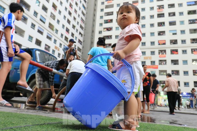 Em bé cũng phải xách xô nước giúp bố mẹ xếp hàng lấy nước ở khu Linh Đàm. Ảnh: Như Ý.