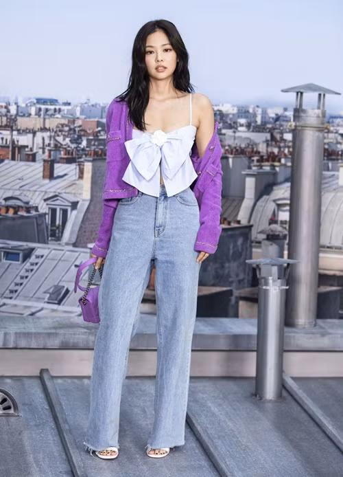 Áo hai dây thắt nơ của nhà mốt Chanel được Jennie phối với cardigan tím cùng jeans ống rộng và túi xách xuyệt tông. Set đồ trông tươi trẻ nhưng khá nhạt nhòa khi dự fashion show, khiến cho Jennie bị chê rất nhiều. 