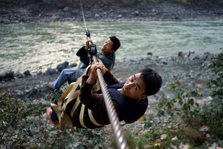 Hai nam giới cùng đu qua sông.