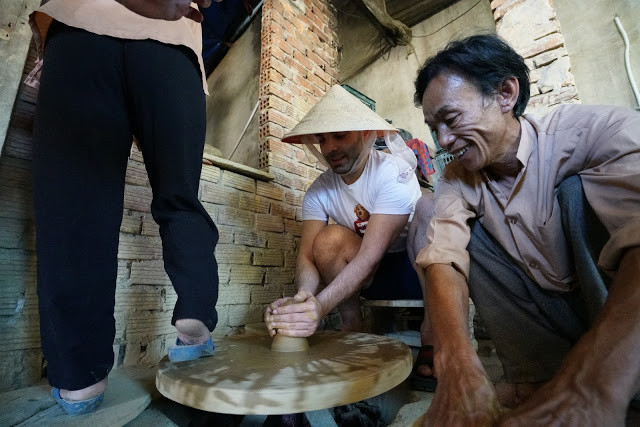 YouTuber Emrah Tekin đang trải nghiệm làm gốm thủ công với bàn xoay đạp chân cùng nghệ nhân tại Làng gốm Thanh Hà