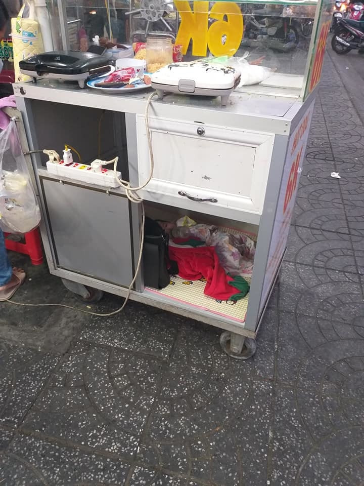 Người mẹ với đứa con thơ năm ngoan ngoãn trong chiếc xe đẩy hàng.