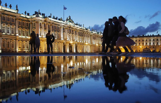 Vài người đang tản bộ lúc nửa đêm ở Quảng trưởng Dvortsovaya, khung cảnh đằng sau là Cung điện Mùa Đông.